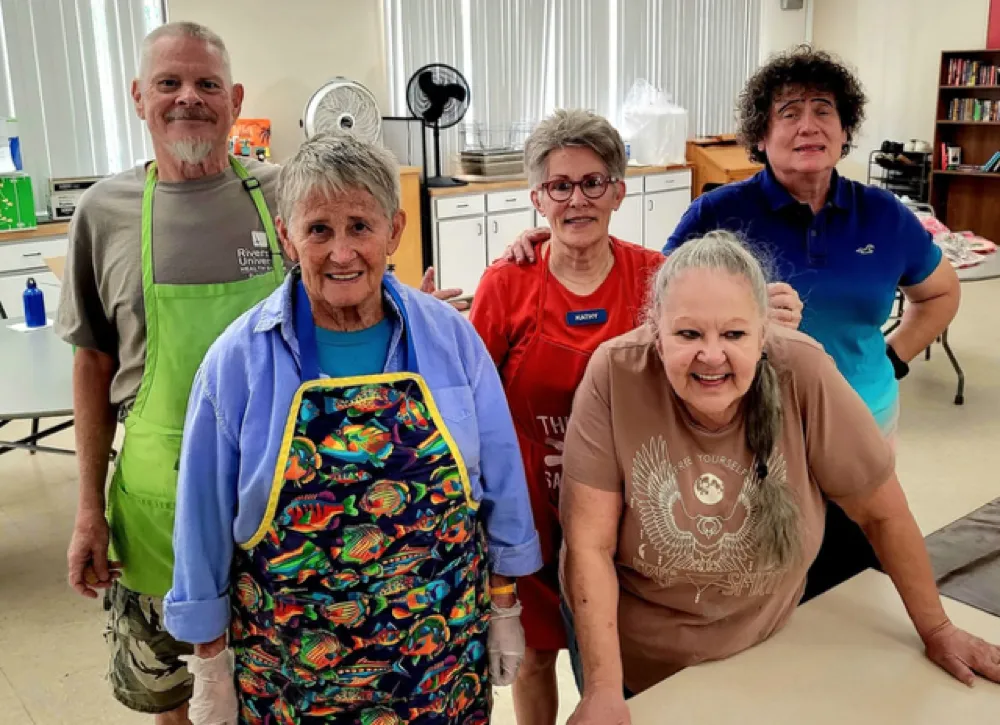 Daily volunteers smiling together in the Well in the Desert kitchen
