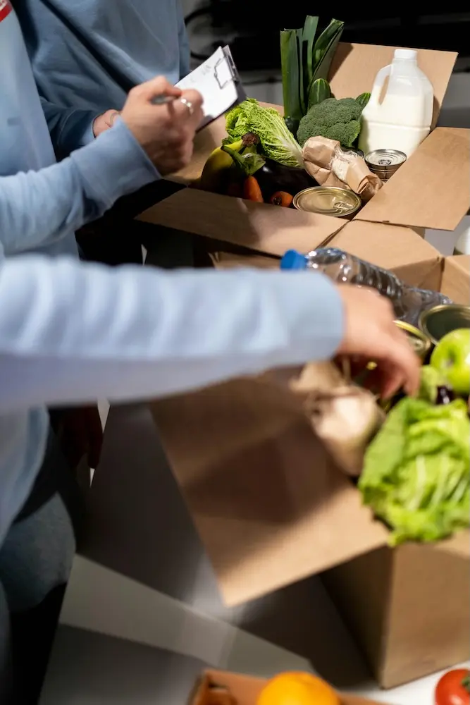Volunteers packing fresh produce and food items into boxes for distribution