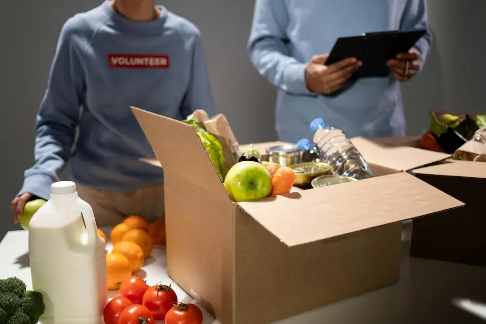 Volunteer in Well in the Desert shirt packing meals at community table